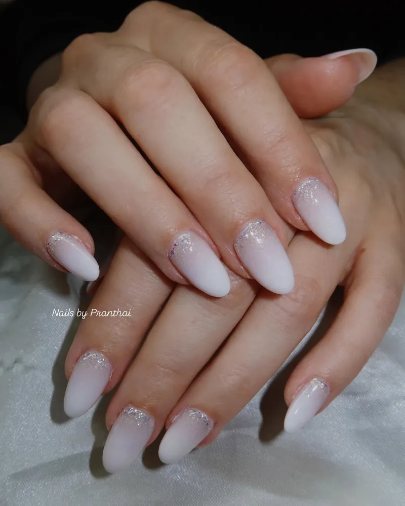 Milky white almond nails with a soft shimmer at the cuticle