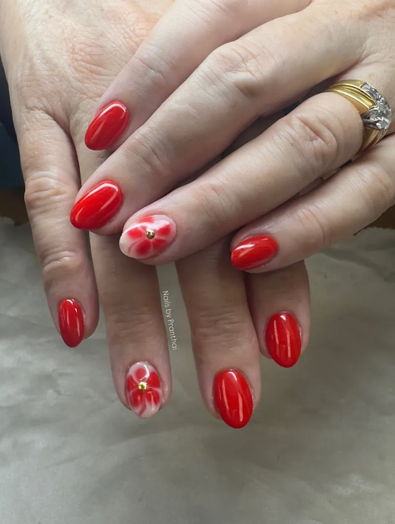 Glossy red nails with white floral accent nails